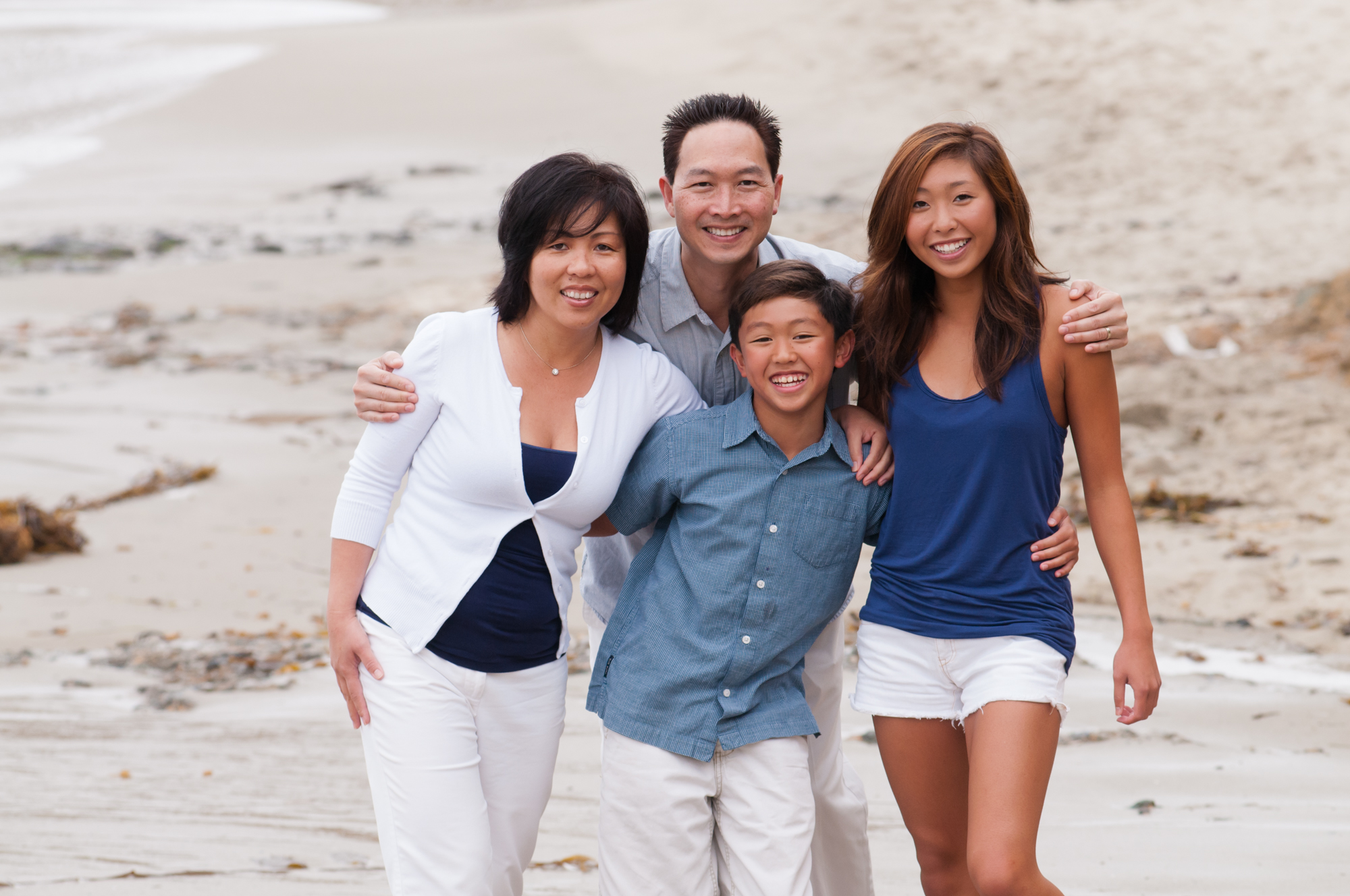 This photograph features an Asian family having casual family photos on the beach near The Montage Hotel in Laguna Beach. The family is wearing color coordinated outfits.